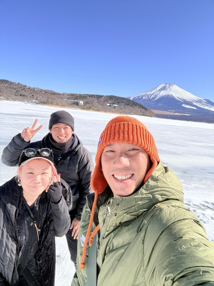 A smiling selfie with guests on a frozen lake below Mt. Fuji