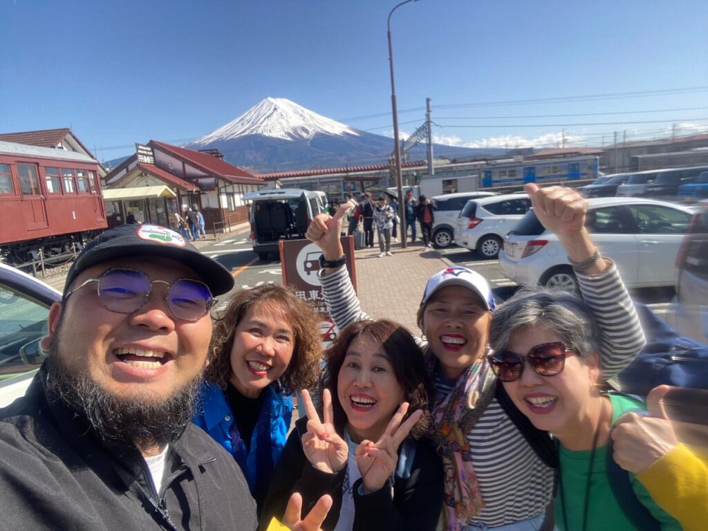 A guide and smiling guests on a private tour, with Mt. Fuji in the background