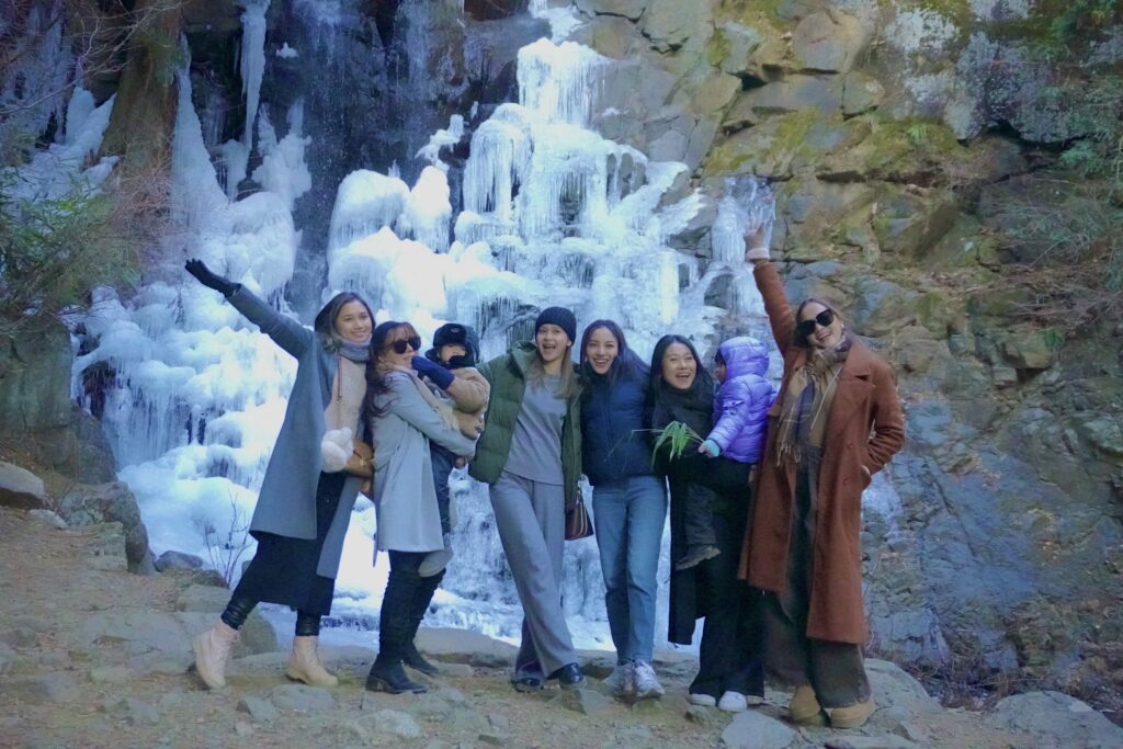 Guests posing in front of a frozen waterfall on a winter tour near Mt. Fuji