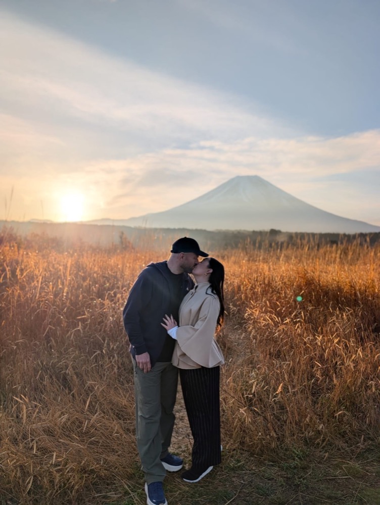 A couple in golden autumn grass at sunset with Mt. Fuji on the horizon
