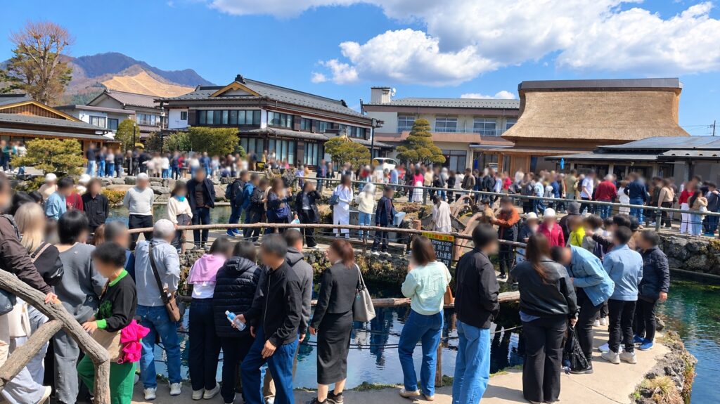 Crowds of visitors around the ponds at Oshino Hakkai at a busy time of day, with faces blurred